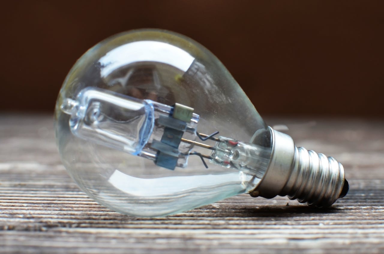 A detailed view of a clear light bulb lying on a wooden surface, symbolizing ideas and innovation.